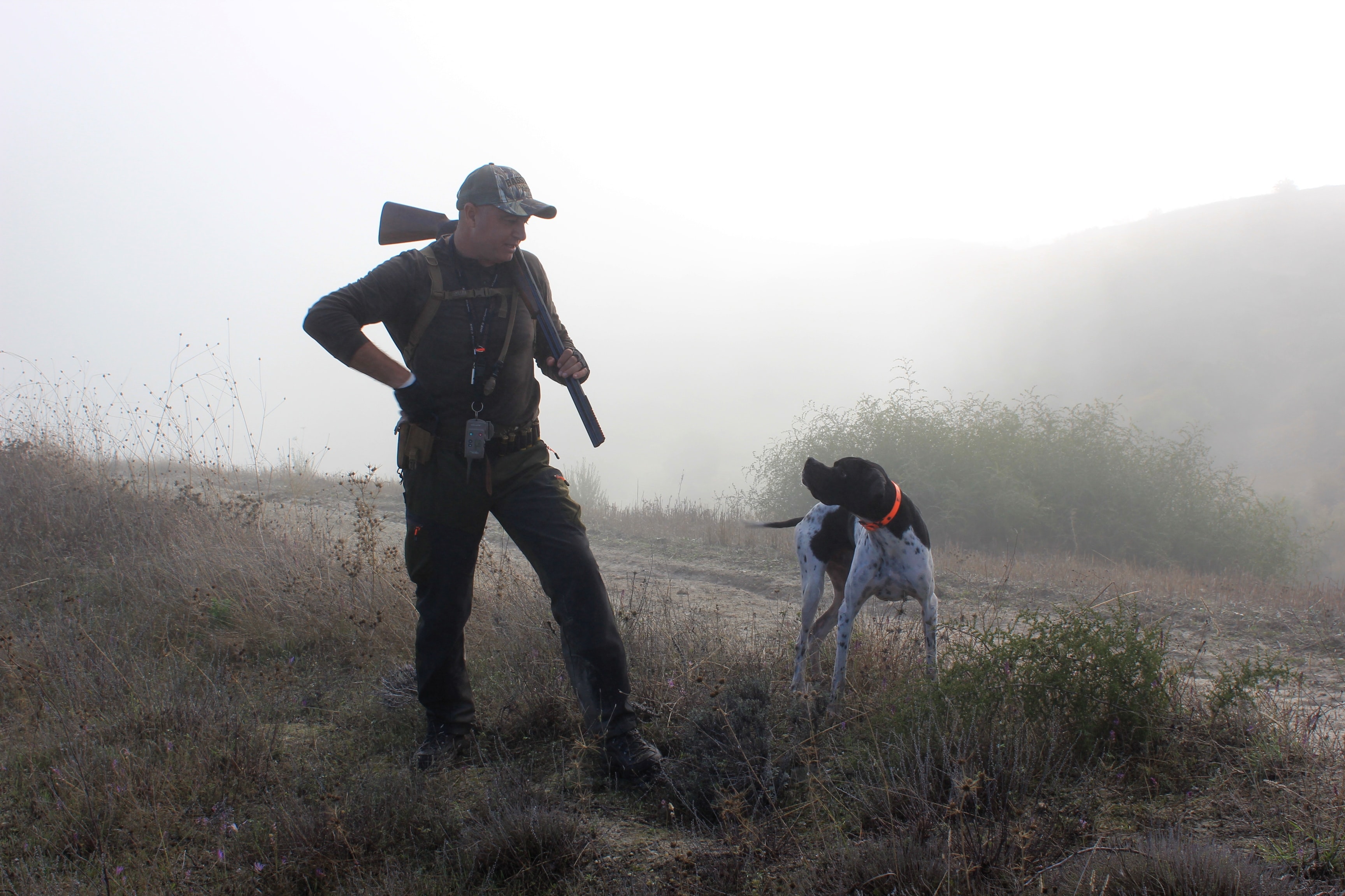 a hunter and his dog in field 