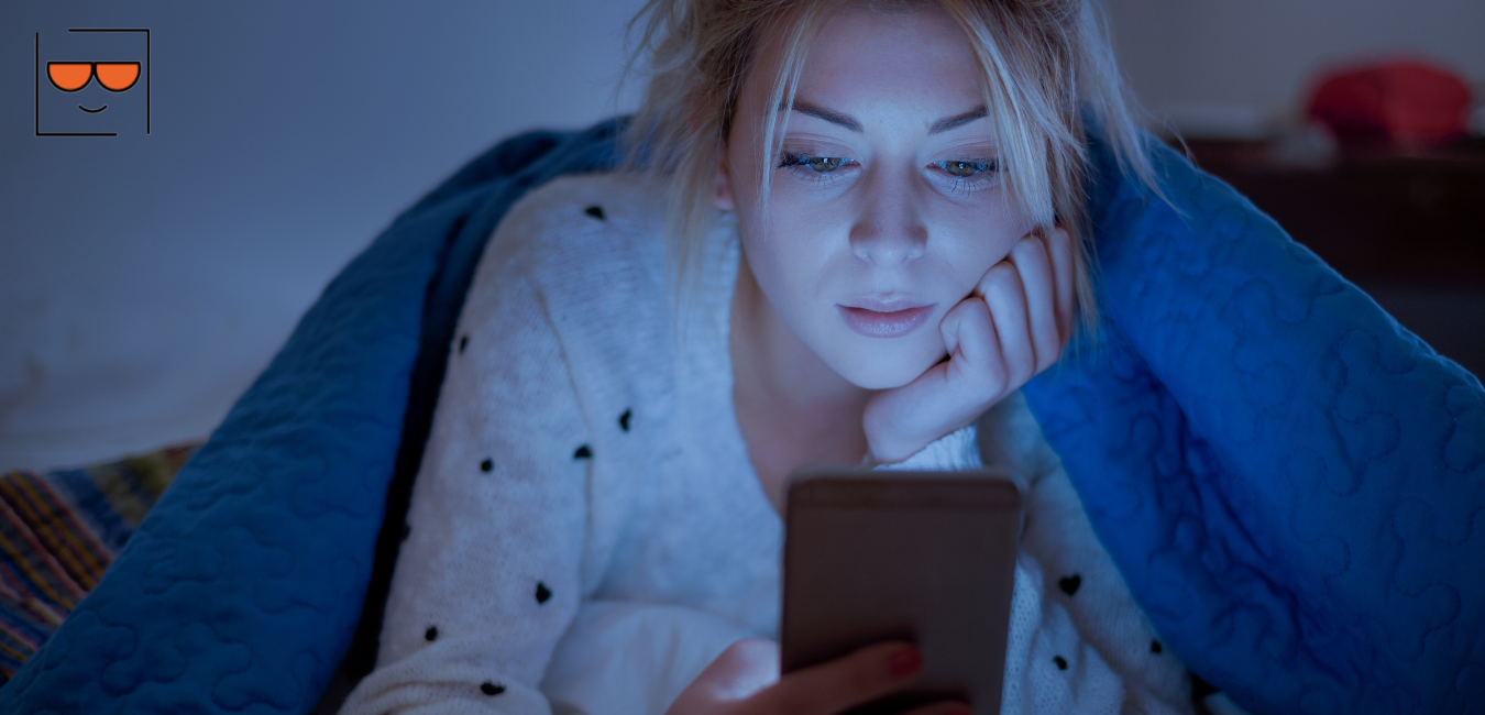 Woman looking at her cell phone in bed
